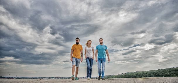 United threesome true friends. United group purposefully moves forward. Friendship tested for years. Men and woman walks dramatic cloudy sky background. True friendship grow with destiny obstacles - Foto, immagini