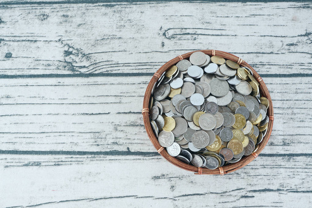 basket filled with coins on white wooden surface - Photo, Image