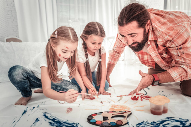 Cute girls and their dad drawing in light bedroom - Foto, imagen