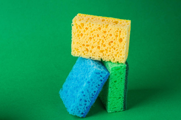 Empiler des blocs géométriques construction éponges abstraites en jaune, bleu, couleurs vertes, sur fond de papier vert, espace de copie
 - Photo, image