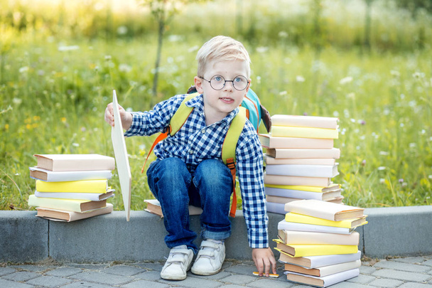 Kleine school jongen met een rugzak en boeken. Het concept van leren, school, geest, lifestyle en succes. - Foto, afbeelding