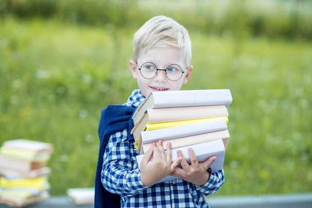 A small strong boy holds a lot of textbooks in his hands. The concept of learning, school, mind, lifestyle and success. - Fotoğraf, Görsel
