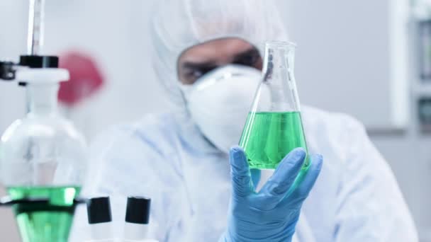 Biotechnologist looking at a sample with green liquid - Séquence, vidéo