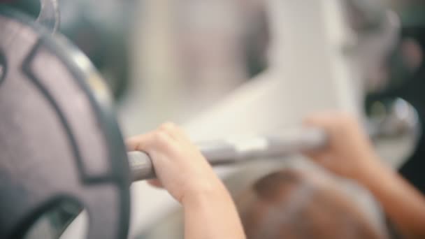 Een atleet vrouw training in de sportschool-krijgt onder de halter en duwen het omhoog - Video