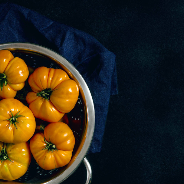 verschiedene Tomaten in einem Sieb auf schwarzem Hintergrund gewaschen - Foto, Bild
