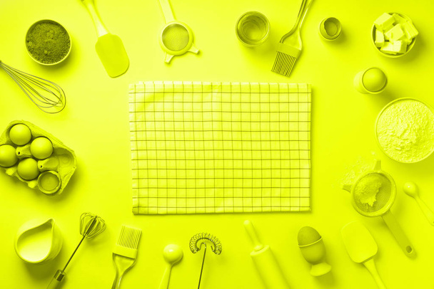 Bakery ingredients over trendy neon yellow color background - butter, sugar, flour, eggs, oil, spoon, rolling pin, brush, whisk, towel. Baking frame, cooking concept. Top view, copy space. Flat lay - Photo, Image