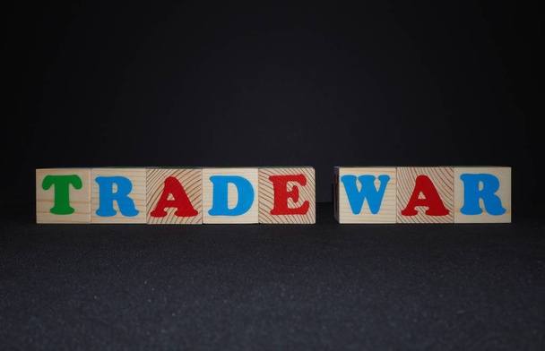 テキストと木製のアルファベットのおもちゃのブロック:貿易戦争。コピースペースを持つ黒い背景に孤立した子供の多色Abcキューブ。アメリカと中国の貿易戦争概念. - 写真・画像