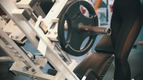 Uma mulher atleta treinando no ginásio - sentada no aparelho de treinamento
 - Filmagem, Vídeo