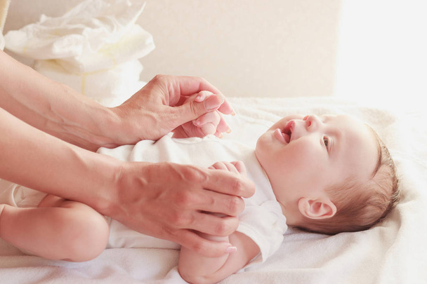 Baby and hands of mother, indoors, blurred background - Fotó, kép
