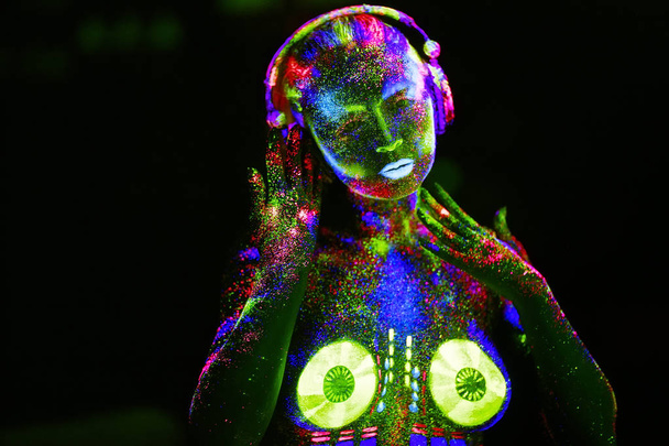 Έννοια. Στο σώμα ενός κοριτσιού που ζωγράφισε το κατάστρωμα για DJ. Μισόγυμνη κορίτσι ζωγραφισμένο σε UV χρώματα - Φωτογραφία, εικόνα