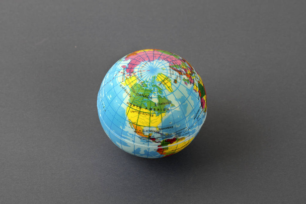 studio shot of small earth planet globe toy isolated on grey  - 写真・画像