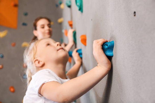 Маленькая девочка лазает по стене в спортзале
 - Фото, изображение