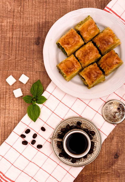 Турецкие деликатесы - пахлава традиционные сладости с турецким кофе, сахар вид сверху на деревянный стол и белую ткань
 - Фото, изображение