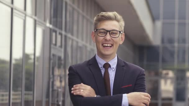 Portrait man in suit in front of office building. Handsome businessman outdoor. Male business person stands on street and looking away. Businessman dressed in formal clothes and glasses. - Video, Çekim