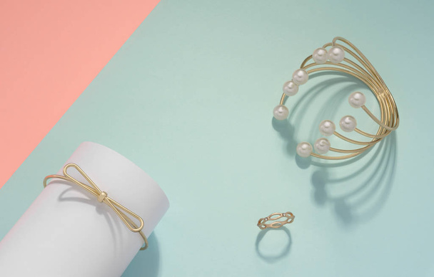 Pulsera de perlas doradas y anillo de oro sobre fondo de color pastel con espacio para copiar
 - Foto, imagen