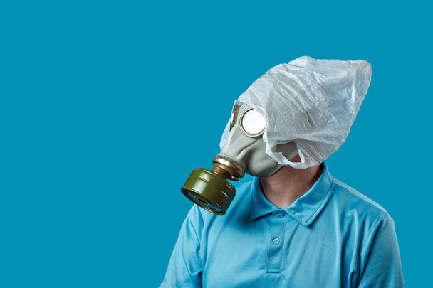 a man in a gas mask and a plastic bag on his head symbolizes the protection of the environment from pollution on blue background - Φωτογραφία, εικόνα