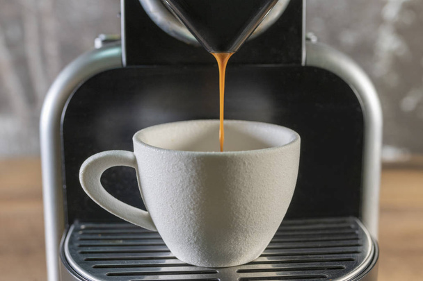 eine Espressomaschine, die Kaffee in eine weiße Tasse gießt - Foto, Bild