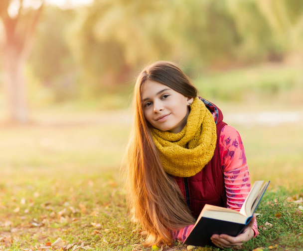 Joyeux jeune adolescent avec livre dans le parc d'automne
 - Photo, image