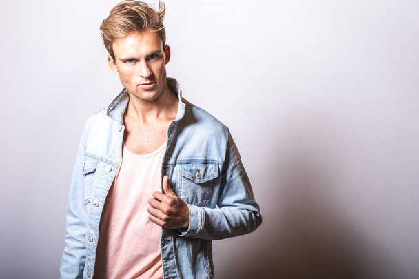 Handsome young man in jeans jacket pose in studio. - Valokuva, kuva