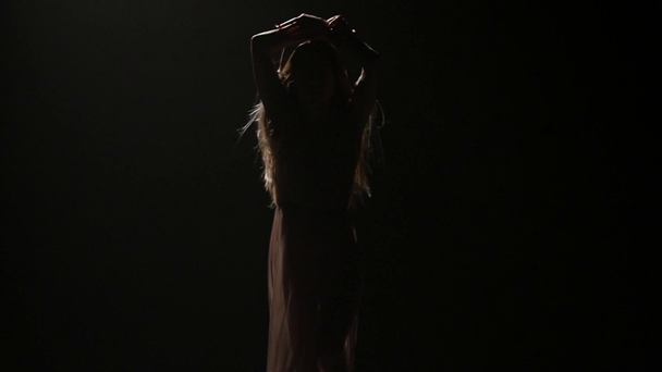 Dark studio, woman with long hair dancing in twilight. Slow motion - Кадры, видео