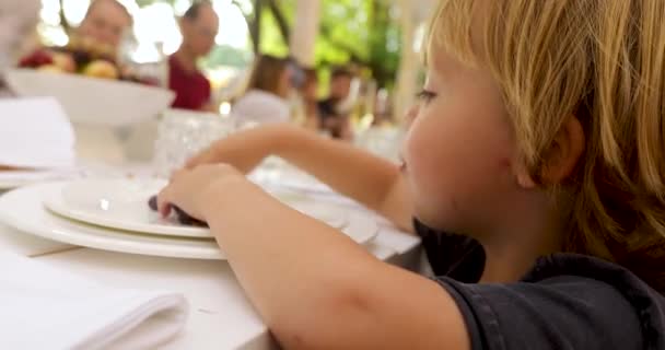 Curios lapsi syö viinirypäleitä pöydässä ulkopuolella ravintola
 - Materiaali, video