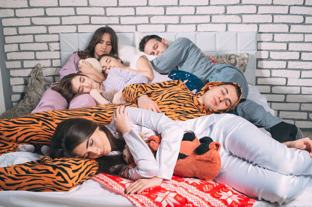 Sleeping group of young people on the bed. - Фото, зображення