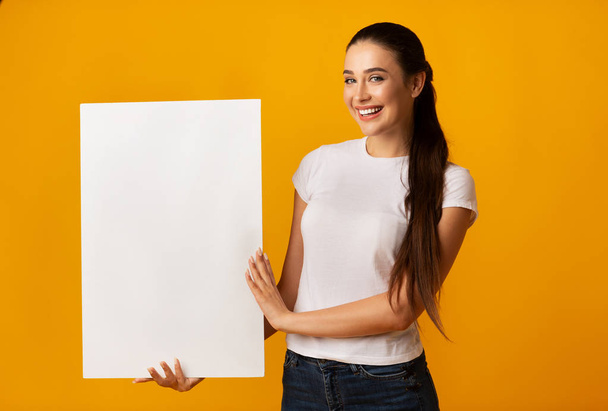 Young Lady Holding Blank White Board On Yellow Background - Фото, зображення