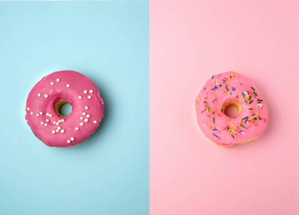 two whole round pink donuts with colored sprinkles lie on a blue - Φωτογραφία, εικόνα