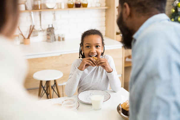 Симпатичная афро девушка ест печенье на завтрак
 - Фото, изображение