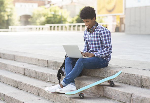 Junge männliche Studentin sticht mit Laptop ins Freie - Foto, Bild