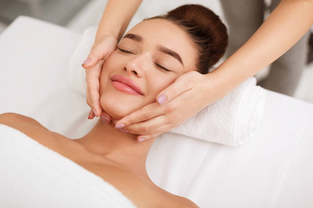 Massagem facial. Mulher recebendo tratamento de spa no salão
 - Foto, Imagem