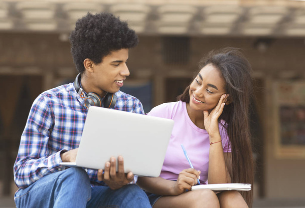 Jovens estudantes africanos trabalhando no laptop juntos ao ar livre
 - Foto, Imagem
