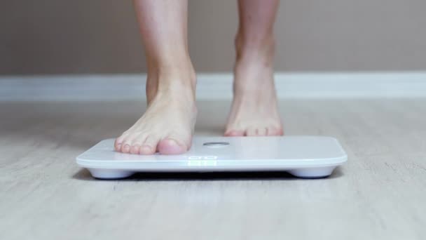 Καθημερινή μέτρηση βάρους, τα γυναικεία πόδια στέκονται σε ψηφιακές έξυπνες κλίμακες - Πλάνα, βίντεο