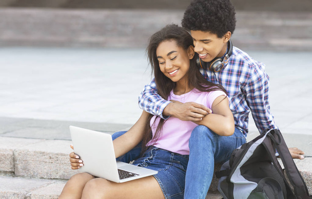 Двое влюбленных подростков используют ноутбук на открытом воздухе вместе
 - Фото, изображение