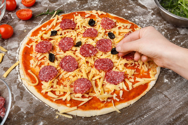 Ev yapımı pizza. Pizzaya siyah zeytin ekleyen kadın - Fotoğraf, Görsel