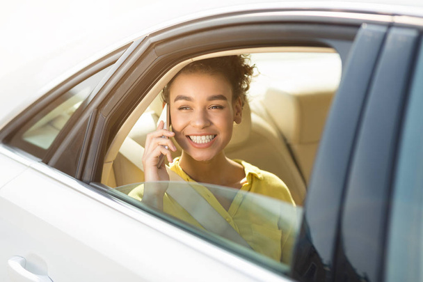 Afro girl talking on phone, sitting in car - 写真・画像