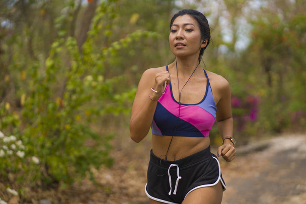 joven atractivo y exótico asiático indonesio corredor mujer en trotar entrenamiento al aire libre en campo camino pista naturaleza corriendo sudoroso empujando duro
 - Foto, Imagen