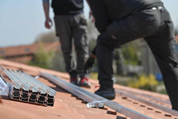 κτίριο Εργαζόμενοι εγκατάσταση μεταλλικών υποδομών για ηλιακούς συλλέκτες στην οροφή κατοικιών - Φωτογραφία, εικόνα