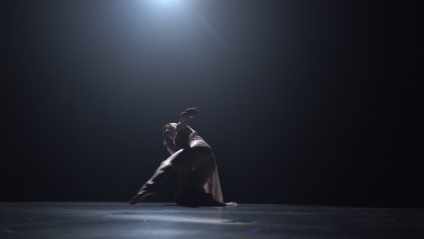 Woman dancing contemp in dark studio against spotlight - Πλάνα, βίντεο