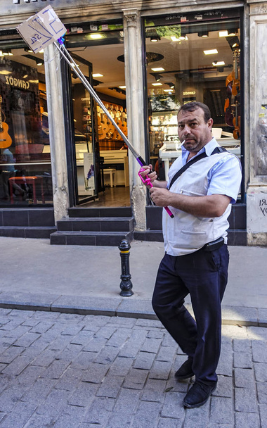 Ortakoy, Turkije - 30 april 2016 - De man loopt op straat en verkoopt selfie sticks - Foto, afbeelding