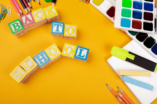 Back to school concept. Colored wooden alphabetical cubes on bright yellow background - Valokuva, kuva