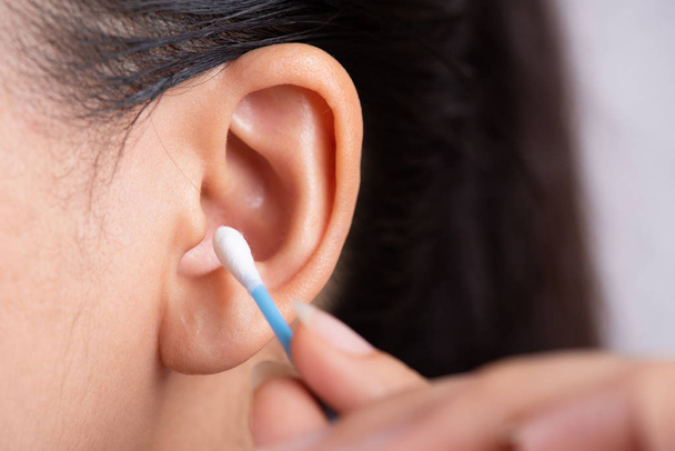 Close up young asian woman cleaning ear with cotton swab. Healthcare and ear cleaning concept. - Photo, Image