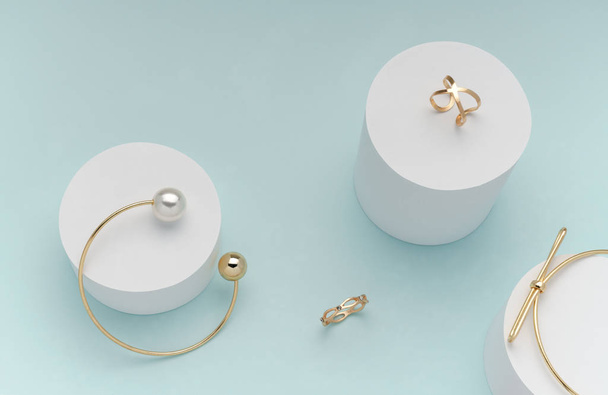 disposición plana de pulseras de oro y anillos en cilindros blancos sobre fondo de color pastel brillante
 - Foto, imagen