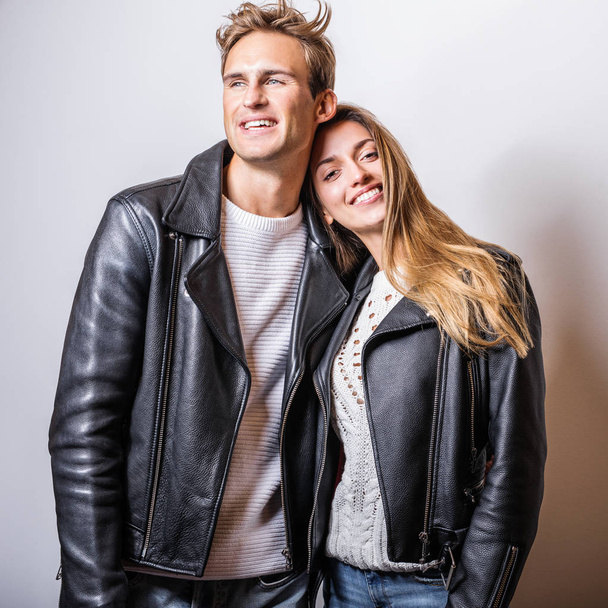 Young beautiful couple in black leather jackets pose in studio. - Valokuva, kuva