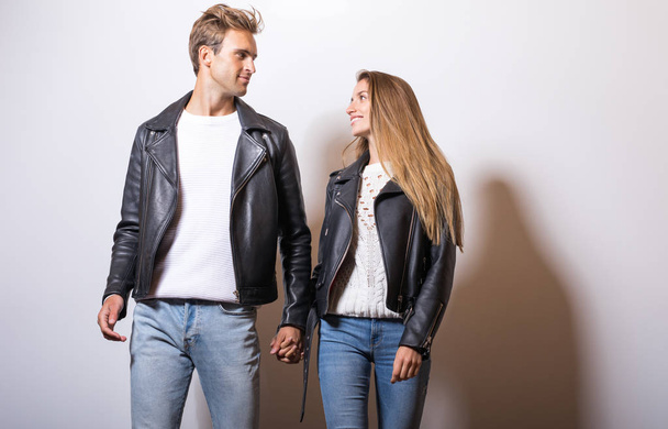 Young beautiful couple in black leather jackets pose in studio. - Foto, Imagem