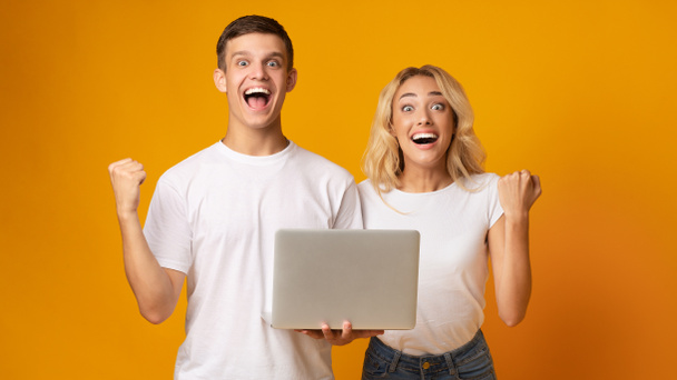 Emocionado casal de jovens comemorando vitória com laptop
 - Foto, Imagem