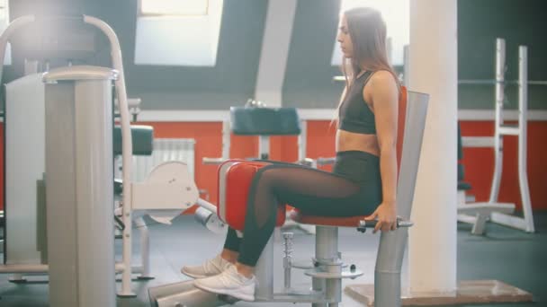 Trening kobieta sportowiec w siłowni wykonywania nóg ćwiczenia na motyla aparat treningowy - Materiał filmowy, wideo