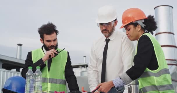 Grupa budownictwa biznesmen architekt i inżynier analizujący plan budowy budynku, noszą kaski ochronne i okulary ochronne - Materiał filmowy, wideo