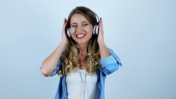 young beautiful sexy blonde woman dancing in headphones feeling happy on isolated white background - Imágenes, Vídeo