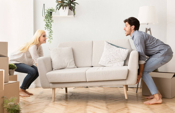 junges Paar trägt Couch am Umzugstag in neue Wohnung - Foto, Bild